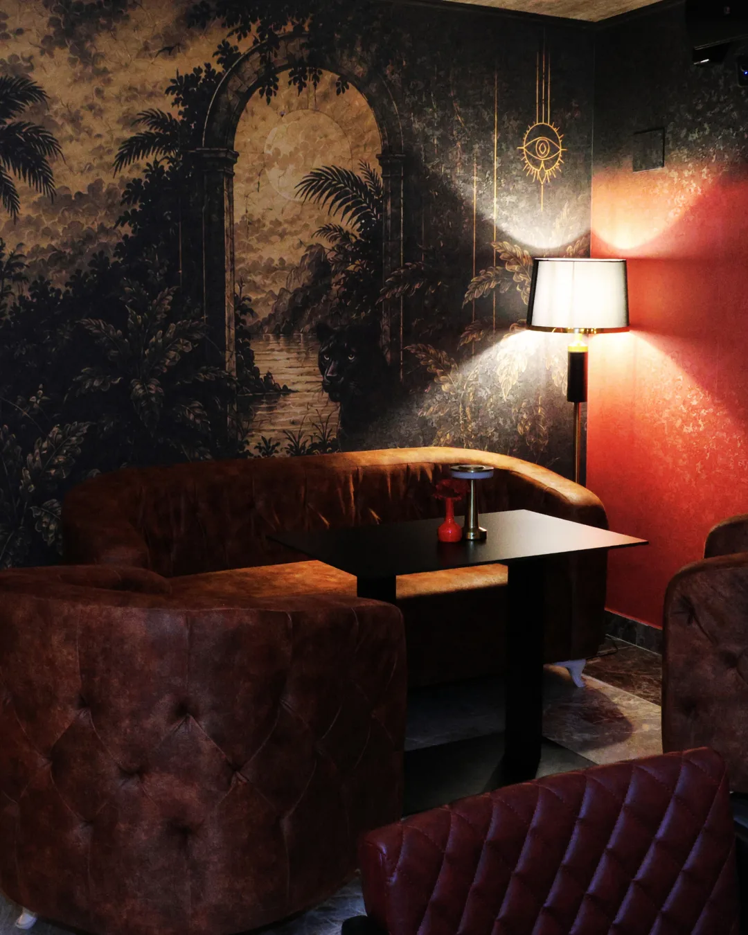 Leather armchairs under a jungle mural in the low-lit lounge at Obscura, Blloku