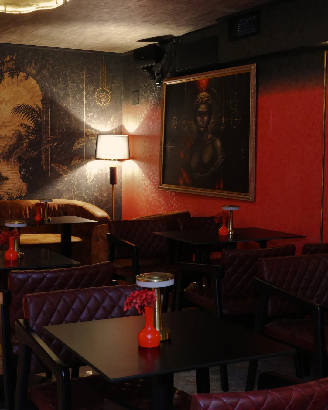Dark red lounge at Obscura cocktail bar in Tirana, with leather chairs, low lamps and a portrait painting