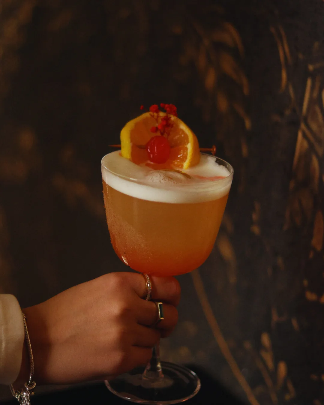 Sour cocktail with a foam top, orange wheel and cherry at Obscura in Tirana